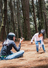 mother and daughter in a pine forest, enjoying nature, meditating and playing with trees