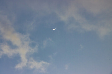 Crescent moon against an evening blue sky.