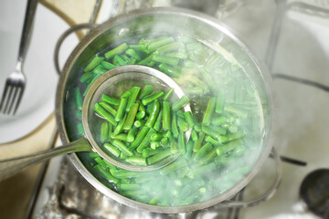 Boiled green beans in a pot, top view. Green bush beans boiling in hot water.