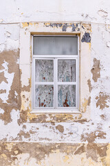 Window in a white stucco building with peeling paint.