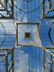 An interesting combination of glass and metal in Palacio de Cristal located in the de El Retiro park in Madrid on a sunny day, Madrid, Spain.