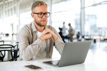 Thoughtful busy caucasian man with glasses, in casual wear, IT specialist, software tester,...