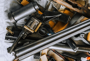 Retro firearms, rifle with ammunition, revolver with cartridges, parts and accessories close-up lie on the table. Close-up photo.