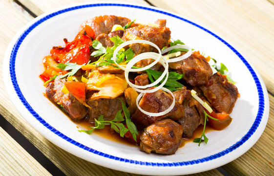 Cooked fried pork meat with peppers, mushrooms and onion served on plate