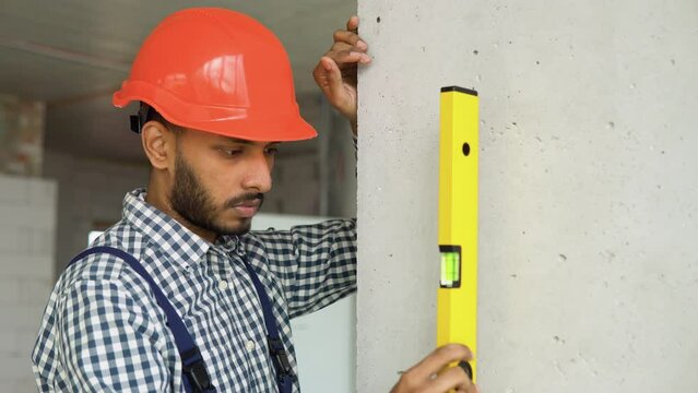Indian or pakistani engineer measures of the vertical deviation of the wall. Bubble level ruler close up view, measuring and leveling concept