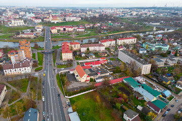 Top view of the historical center of the city. Flying a drone over the roofs of houses and a bridge over the river. The long main street of the city during the day.