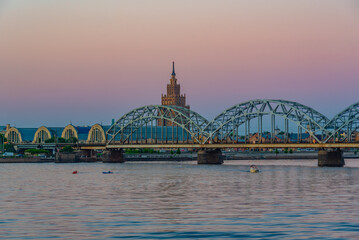 Sunset view of the zeppelin hangars and the academy of sciences building next to a steel railway bridge in the Latvian capital Riga. © dudlajzov