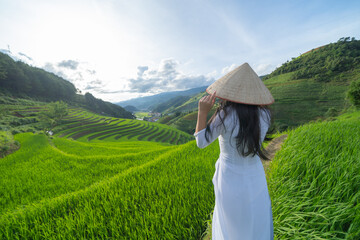 Fototapeta na wymiar A farmer with fresh paddy rice terraces, green agricultural fields in countryside or rural area of Mu Cang Chai, mountain hills valley in Asia, Vietnam. Nature landscape. People lifestyle.
