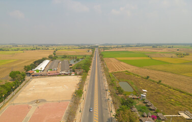 Aerial top view of road street with paddy rice terraces, green agriculture fields in countryside, mountain hills valley, Thailand. Nature landscape. Crops harvest.