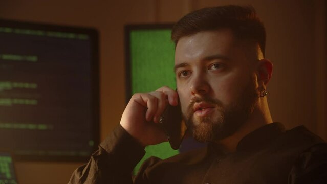 An employee of an IT company is sitting in his office and talking on the phone. A male programmer tells his colleague on the phone about the bugs found in the application.