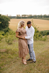 Man with beard is touching belly of his pregnant wife from in nature.