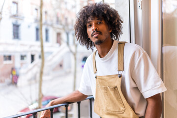 Portrait of a young black ethnic man on a balcony at home, everyday situation, apartment