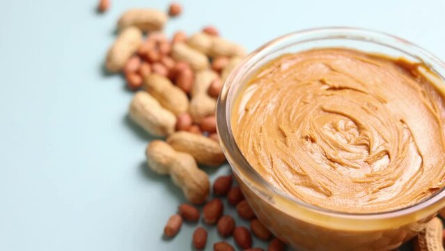peanut butter and raw peanuts on a colored background