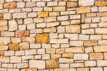 Ściana budynku z obrobionych kamieni piaskowca . Bloki ( cegły ) żółto- białego piaskowca jako części składowe murku . - obrazy, fototapety, plakaty