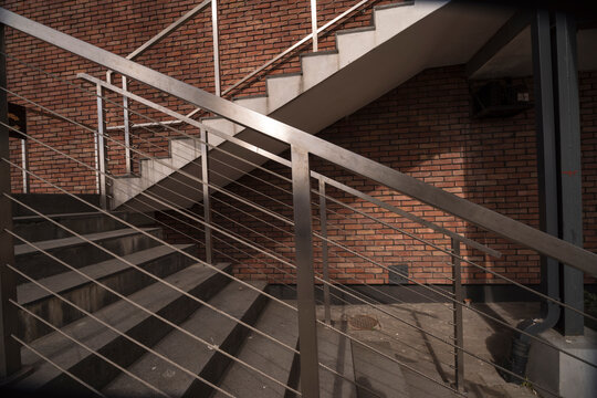 Fototapeta Dizajnerskie schodki z poręczami z profilów ze stali nierdzewnej i stalowych linek . Ściana z czerwonej cegły klinkierowej .