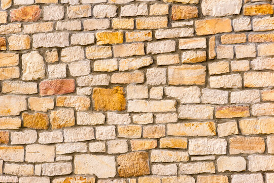 Fototapeta Ściana budynku z obrobionych kamieni piaskowca . Bloki ( cegły ) żółto- białego piaskowca jako części składowe murku .