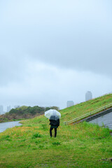 雨の日に河川敷を歩く人