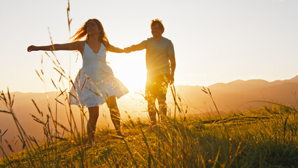 Man and woman dance on the summer meadow with grass at sunrise