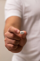 Vertical view hand holding a pill with a happy face in the medicine pill with close up and bokeh background