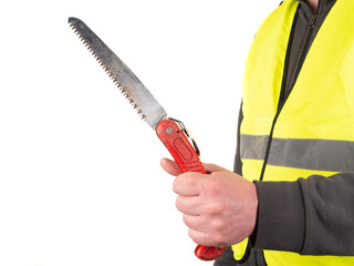 A worker holding a foldable pruning saw in his hand. The person wears a yellow security jacket....