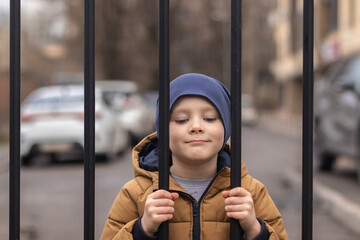 Obraz premium Portrait of a little boy behind a chain link fence
