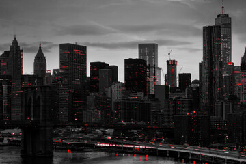 Red lights shining in black and white night time cityscape with the Brooklyn Bridge and buildings...