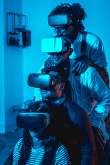 Naklejka premium Group of young people with vr glasses in a virtual reality game in a blue light, in formation on top of each other, futuristic or science, technology concept