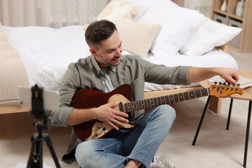 Music teacher tuning guitar while conducting online lesson at home. Time for hobby