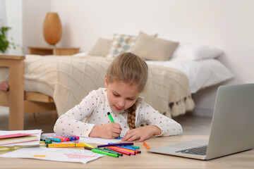 Little girl drawing with felt-tip pen following online course at home. Time for hobby