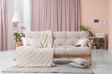 Comfortable sofa, cushions and blanket in cozy room. Interior design