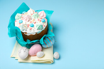 Traditional Easter cake with meringues and painted eggs on light blue background, space for text