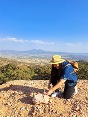 Latina woman with hat and miner's pick hammer works as a geologist, studies the composition and...