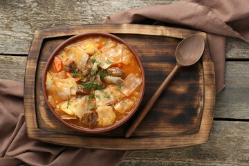 Tasty cabbage soup with meat, carrot and dill on wooden table, top view