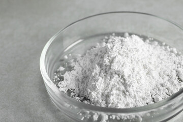 Petri dish with calcium carbonate powder on light grey table, closeup