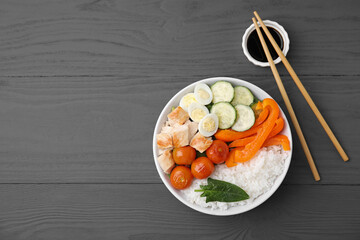 Delicious poke bowl with meat, rice, eggs and vegetables served on wooden table, flat lay. Space for text