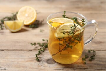 Aromatic herbal tea with thyme and lemon on wooden table, space for text