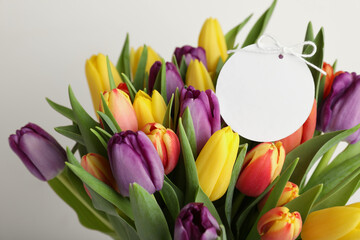 Bouquet of colorful tulips with blank card on white background, closeup