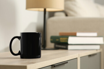 Black mug on wooden table indoors. Mockup for design