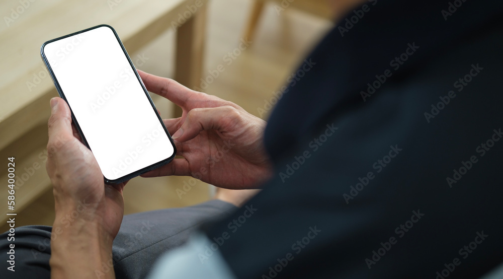 Poster close up view of man sitting in living room and using mobile phone. blank screen for your text messa