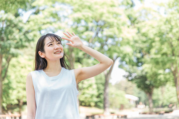 新緑の中で日光を浴びる日本人女性（紫外線対策・日焼け止め）
