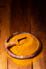 Turmeric Powder in a Wooden Spoon and Bowl