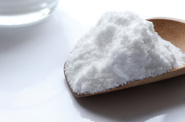 Close-up of Baking soda (sodium bicarbonate) with wooden spoon on white table. Home cleaning concept.