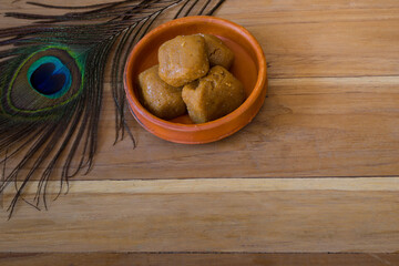 Mathura ka peda is served on a clay plate with peacock feather during celebration of Krishna janmashtami. This traditional Indian sweet originated in mathura is made of khoya or Mawa, ghee and sugar. - obrazy, fototapety, plakaty
