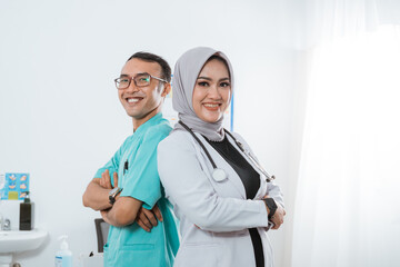 a beautiful doctor with grey veil standing with hand crossed back to back with the male nurse in...
