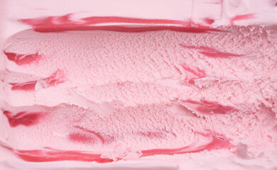 Close-up shot of strawberry ice cream texture shoveled from a steel spoon.