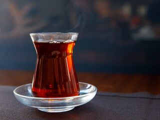 Turkish tea in a traditional glass in shape of tulip called Bardak against the background of cafe. Holiday in Turkey, travel resort