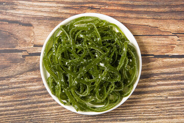 Fresh shredded kelp in plate on table.