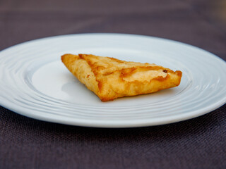 Delicious turkish pie filo pastry with greek feta cheese triangle pie close-up on white plate on the table. side view, horizontal.