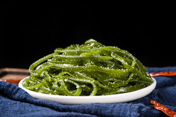 Fresh shredded kelp in plate on table.