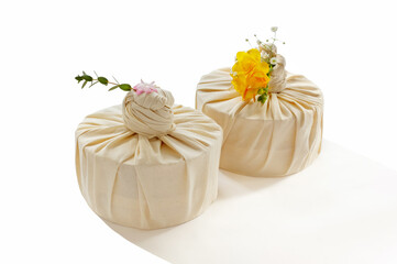 Korean traditional gift wrapped in cotton (bojagi) and decorated with flower for holidays and special anniversary. Isolated on white background.
